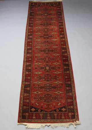 A red ground machine made Afghan style runner with 13 stylised diamonds to the centre within a multi row border 343cm x 90cm 
