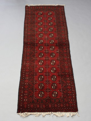 A red ground Afghan runner with 26 octagons to the centre within a multi row border 240cm x 82cm 