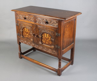 A 17th Century style carved oak side cabinet fitted 2 drawers above a pair of cupboards enclosed by carved arched and inlaid panelled doors raised on turned and block supports 84cm h x 99cm w x 41cm d 