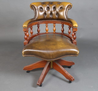 A Georgian style mahogany revolving office chair with bobbin turned decoration, upholstered in green buttoned leather