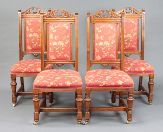 A set of 4 Victorian carved walnut show frame dining chairs, seats and backs upholstered in floral material with over stuffed seats, raised on cup and cover supports with  H framed stretcher 