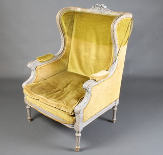 A French style winged armchair upholstered in yellow material, raised on turned and fluted supports 
