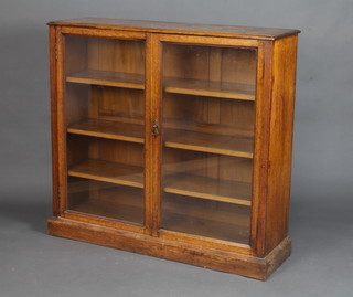 A Victorian light oak display cabinet/bookcase fitted shelves enclosed by glazed panelled doors, raised on a platform base 113cm h x 122cm w x 37cm d 
