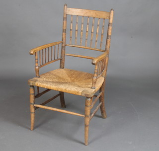A William Morris style elm stick and rail back carver chair with woven rush seat 