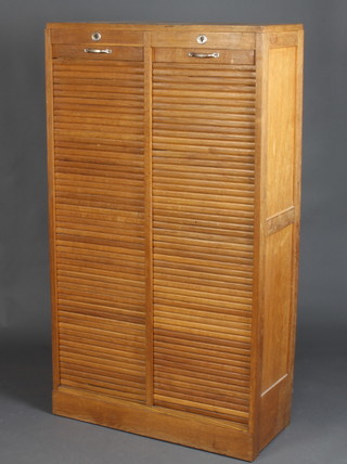A 1930's light oak 2 section filing cabinet fitted shelves enclosed by a tambour shutter 148cm h x 83cm w x 37cm d 