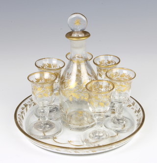 A 19th Century glass and gilt decorated liqueur set comprising decanter 14cm, 6 tots 7cm and a circular glass tray 17cm 