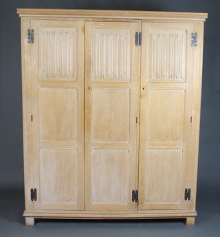A Heals White Spot limed oak triple wardrobe with moulded cornice enclosed by 3 panelled doors with linenfold decoration raised on square feet 183cm h x 152cm w x 59cm d, together with a pair of limed oak linenfold panel end bedsteads complete with irons 117cm x 92cm 