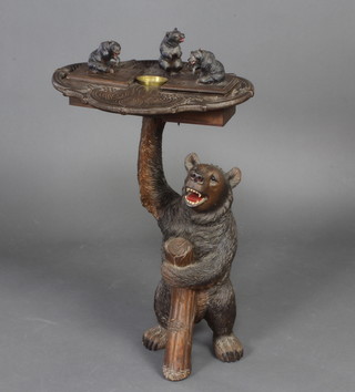 A 19th Century Swiss Black Forest carved pine musical smokers table, the upper section fitted 2 boxes with bear finials and pressed metal ashtray to the centre supported by a standing bear with hinged lid to reveal a void 87cm h x 52cm w x 43cm d 