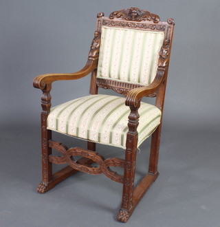An Italian carved oak open arm chair, the crest carved a cherub, the arms carved figures of kneeling ladies, raised on square supports with lattice work stretcher and paw feet 