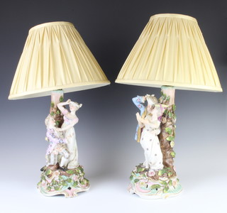 A pair of German porcelain table lamps in the form of a fete gallant couple with applied flowers, raised on rococo bases converted to electricity 30cm 