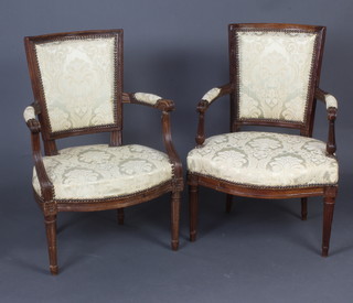 A pair of 19th Century French carved walnut open arm salon chairs, the seats and backs upholstered in yellow material 