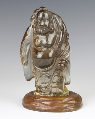 A 20th Century Chinese carving of Budai, the God standing with staff and huge bag in grey-tinted translucent glass or quartz, 14cm,  with stand 
