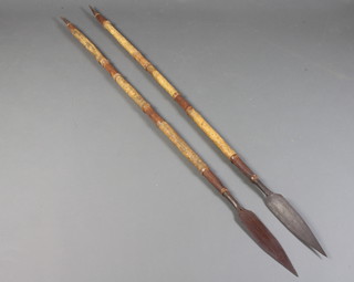 A pair of African spears with 28cm leaf shaped blades, mounted on turned wooden and hide covered shafts 