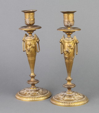 A pair of 19th Century French gilt metal candlesticks with vinery decoration and lion ring drop handles, raised on circular feet 27cm h 