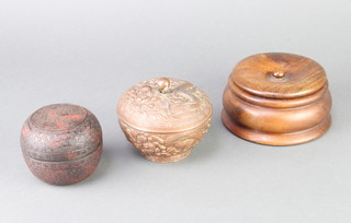 An Oriental circular red lacquered jar and cover 7cm x 8cm (chips to rim), a Chinese antimony jar and cover 9cm x 11cm and a turned mahogany jar and cover 
