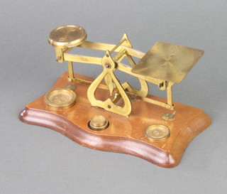 A pair of brass letter scales raised on a mahogany stand with 3 weights 