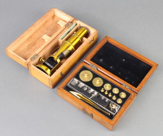 A students gilt metal single pillar microscope in a wooden case together with a cased set of brass weights 