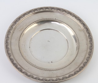 A circular sterling silver dish with repousse scroll decoration 175 grams, 24cm 