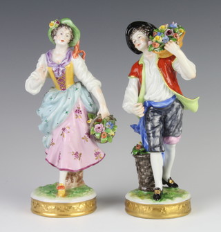 A pair of German porcelain figures of flower sellers raised on circular bases 21cm  