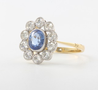 An 18ct yellow gold oval sapphire and diamond cluster ring, the centre stone approx. 1.35ct surrounded by brilliant cut diamonds 0.9ct, size N 1/2