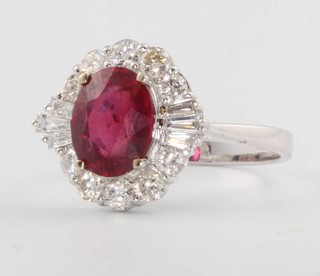 An 18ct white gold oval, treated ruby and diamond cluster ring, the centre stone approx. 2.96ct surrounded by tapered baguette diamonds 0.18ct and brilliant cut diamonds 0.67ct, size N
