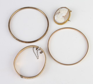 Three gold plated bangles and a cameo portrait brooch 
