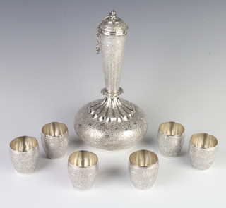 A Persian silver spirit decanter and lid with 6 tots decorated with scrolling flowers 605 grams 