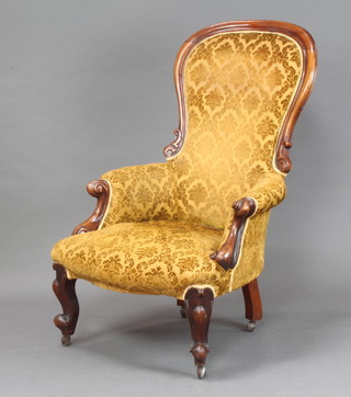 A Victorian mahogany show frame armchair upholstered in yellow material, raised on cabriole supports 