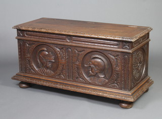 An 18th Century style carved oak coffer with hinged lid, the front panel carved figures of warriors, raised on bun feet 61cm h x 120cm w x 40cm d 