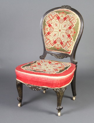 A Victorian carved and ebonised nursing chair, the seat and back upholstered in Berlin woolwork tapestry, raised on cabriole supports 