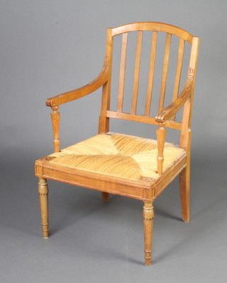 A 19th Century French fruitwood stick and rail back open arm carver chair with woven rush seat, raised on turned supports 
