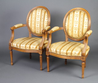 A pair of French walnut open arm salon chairs with upholstered seats and backs raised on turned and fluted supports 