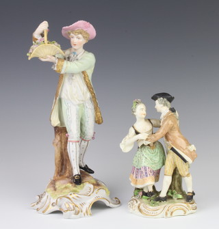 A German figure of a gentleman holding aloft a basket of flowers on a rococo base 28cm, a ditto figure of a dancing couple 16cm 