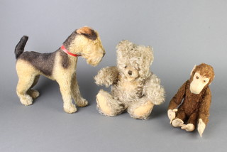 A Steiff style figure of a monkey 27cm, a mohair teddy bear 21cm and a figure of a standing Airedale terrier 26cm 