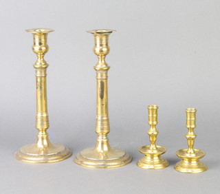 A pair of 17th Century bell metal candlesticks, raised on tapered bases 10cm x 5cm (1 slightly bent) together with a pair of Regency brass candlesticks with engraved decoration 23cm (1 has damage to the sconce) 