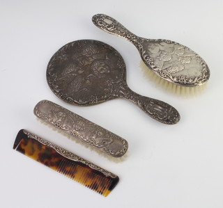An Edwardian style Reynolds Angels repousse silver brush set comprising hand mirror, clothes brush, hair brush and comb, Birmingham 1960 