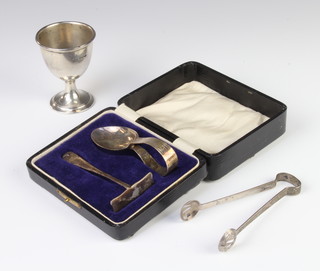 A silver egg cup Sheffield 1922, a pair of tongs and a pusher and spoon, 87 grams