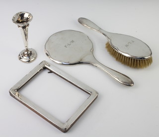 A silver backed dressing table mirror, a brush, a frame and a spill vase 