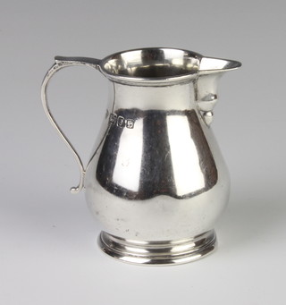 A silver baluster cream jug with simple handle, London 1957, 110 grams 