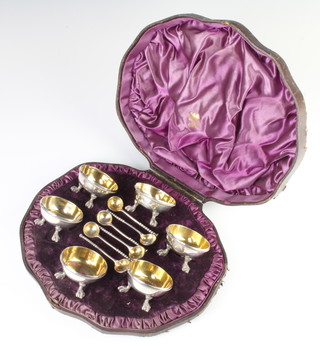 A cased set of 6 Victorian circular silver table salts with gilt interiors raised on claw and ball feet and 6 matching spoons, London 1874 and 1875, 350 grams 