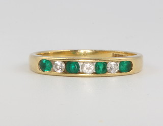 An 18ct yellow gold channel set emerald and diamond ring, size N, 2.6 grams