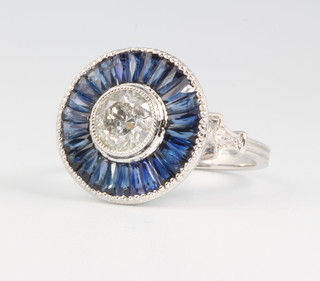 A platinum diamond and sapphire target ring, the centre stone approx. 1.01ct surrounded by calibre cut sapphires and brilliant cut diamonds, size N 1/2