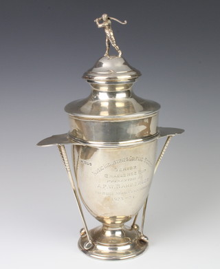 A silver golf trophy with with twin handles in the form of golf woods, the lid with a male golfer, presentation inscription, Music Industries Golfing Society Senior Challenge Cup presented by A P W Bamberger for 18 Hole medal competition 1923-1924, London 1924, 35cm, 929 grams