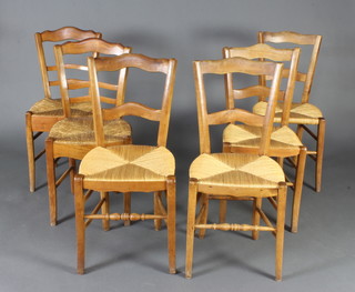 A harlequin set of 6 French elm ladderback dining chairs with rush seats, raised on turned supports (2 carvers, 4 standard) 
