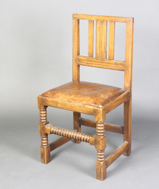 A 17th/18th Century style oak hall chair with upholstered drop in seat raised on bobbin turned and block supports 