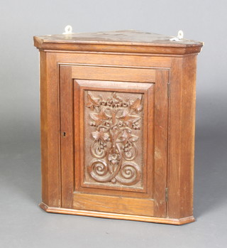 A Victorian carved oak hanging corner cabinet with moulded cornice, fitted shelves enclosed by a carved panelled door 53cm h x 50cm w x 30cm d 