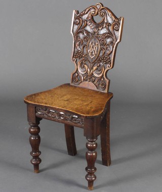 A Victorian carved oak hall chair with shaped seat, raised on turned supports 