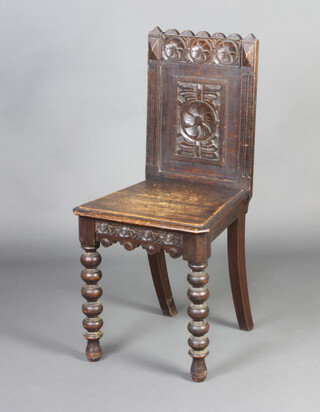 A Victorian carved oak hall chair with solid seat and carved panel back, raised on bobbin turned supports 
