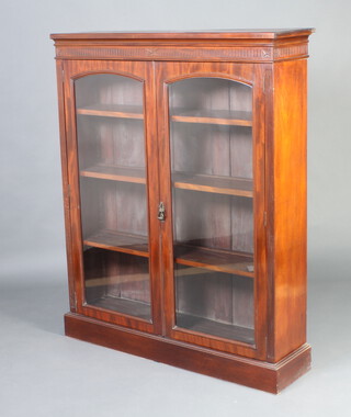 A Victorian mahogany bookcase/display cabinet with fluted cornice, fitted shelves enclosed by arched panelled doors, raised on a platform base 146cm h x 118cm w x 33cm d (formerly the top to lot 1045)