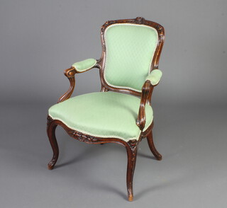 A French 19th/20th Century carved walnut open arm salon chair, the seat and back upholstered in green material
